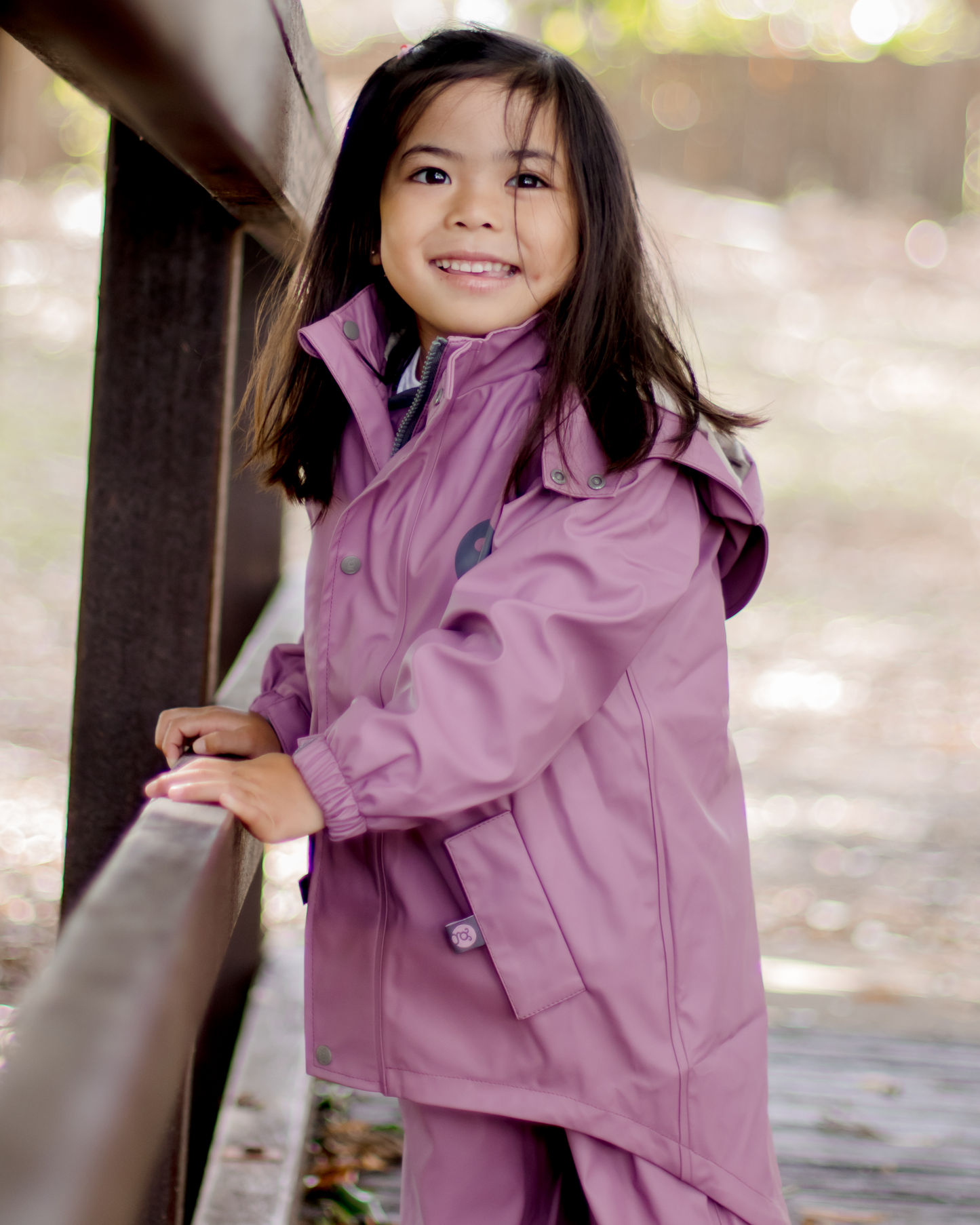 Toddler girl wearing waterproof jacket outdoors, kids all weather raincoat for everyday play