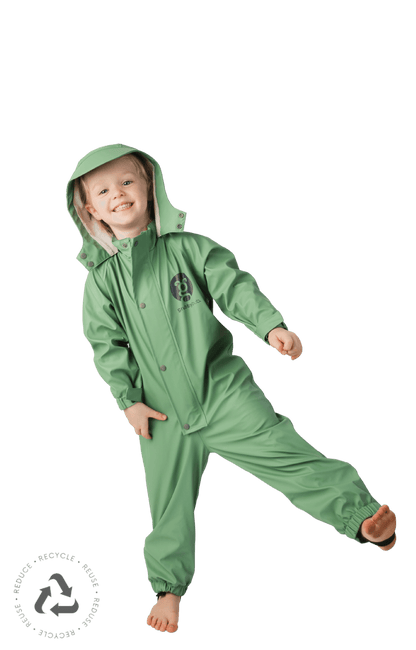 girl in a sage green waterproof puddle suit posing with one foot in the air
